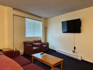 a living room with two chairs and a flat screen tv at Redford Motel in Port Alberni