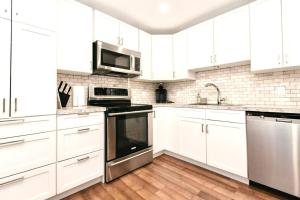 a white kitchen with white cabinets and stainless steel appliances at Esquimalt Lagoon Life in Victoria