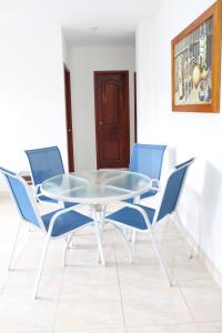 uma mesa de vidro com quatro cadeiras azuis num quarto em CASAS BLANCAS Coveñas em Coveñas
