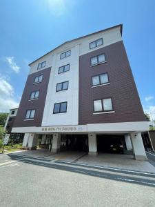 a large brown and white building with a parking lot at Gora Hotel Paipuno Kemuri Plus in Hakone