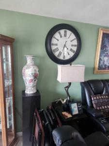 a living room with a clock on the wall and a chair at Beautiful home near mall & beach in St. Petersburg