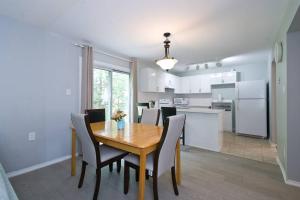 a dining room and kitchen with a wooden table and chairs at Lake Simicoe town cottage near Innisfil Beach Park in Innisfil