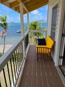 a porch with a yellow chair on the beach at Bahari in Carriacou