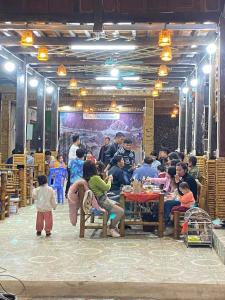 een groep mensen die aan een tafel in een kamer zitten bij Mai Chau Moonlight Ecohouse in Mai Chau