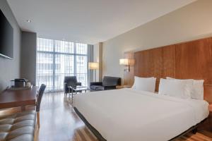 a hotel room with a large white bed and a desk at AC Hotel Aitana by Marriott in Madrid