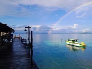 un barco en el agua junto a un muelle con un arco iris en Alter Native Stay, en Tapokreng