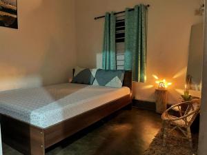 1 dormitorio con cama, ventana y lámpara en Assam Villa - by Storyweavers Retreat, en Jorhāt