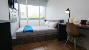 een kleine kamer met een bed, een bureau en een stoel bij My Dormy Hostel UMM in Sengkaling