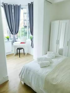 um quarto branco com uma cama grande e uma janela em Prime London Living 2-Bedroom Beauty! em Londres