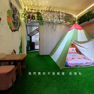 uma tenda no chão num quarto com uma mesa em 棚棚屋室內帳篷民宿Inn em Kaohsiung