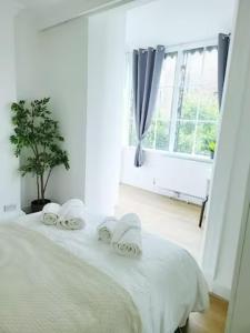 a white bedroom with a bed with towels on it at Prime London Living 2-Bedroom Beauty! in London
