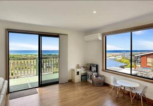 een woonkamer met grote ramen en een tafel en stoelen bij Home @ Scamander Beach in Scamander