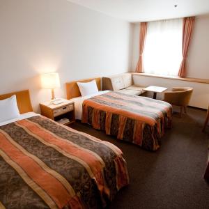 坂出市にある坂出 グランドホテルのベッド2台とソファが備わるホテルルームです。
