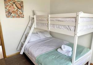 een slaapkamer met 2 stapelbedden en handdoeken bij Home @ Scamander Beach in Scamander