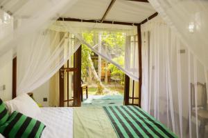 ein Schlafzimmer mit einem Bett und einem großen Fenster in der Unterkunft Shady Cottage in Ahangama