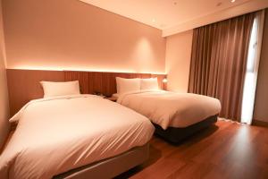 a hotel room with two beds and a window at Busan City Hotel in Busan