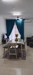 una mesa y sillas en una sala de estar con cortinas azules en MQA Homestay en Sepang