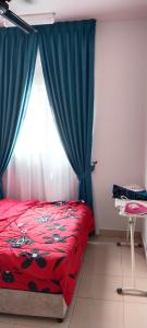 1 dormitorio con cama roja y cortinas azules en MQA Homestay en Sepang