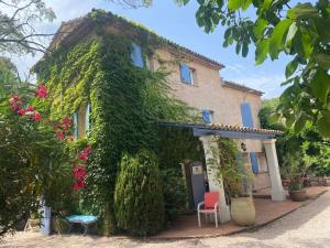 a building covered in ivy with a chair in front of it at Féerie Love in Puget-sur Argens