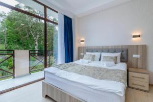 een slaapkamer met een groot bed en een groot raam bij Vita Gardenia Hotel Tskaltubo in Tskaltubo