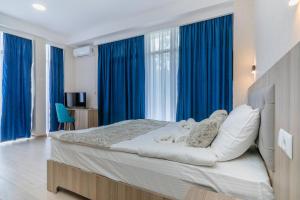 um quarto com uma cama grande e cortinas azuis em Vita Gardenia Hotel Tskaltubo em Tskaltubo