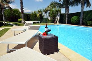 a swimming pool with two chairs and a bottle of wine at Villa Palme in Alcamo Marina