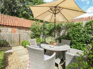 un tavolo e sedie con ombrellone su un patio di Bridge Cottage a Norwich