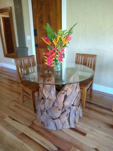 a glass table with flowers on top of a tree stump at Hale Laule'a at Opihi Point - Oceanfront, Gated Estate in Hakalau