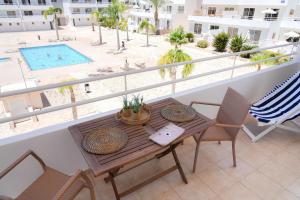 uma varanda com mesa e cadeiras e uma piscina em Narcissos 'Nissi Beach' Apartment E9 em Agia Napa