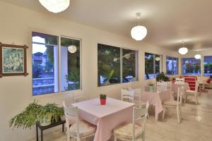 a dining room with tables and chairs and windows at Kiraz Butik Hotel in Alaçatı