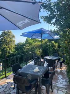 a patio with tables and chairs with a blue umbrella at Feride in Makhinjauri