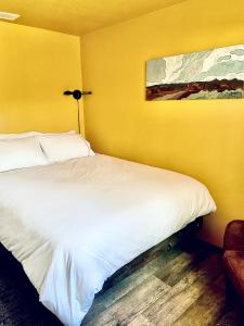 a bedroom with a white bed with a yellow wall at The Finca - Moab's Hidden Gem in Moab