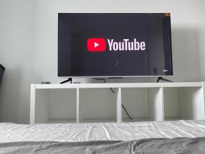 a television sitting on a white stand with a bed at Dtravellers Home 1 at AZURE NORTH BALI Tower in San Fernando