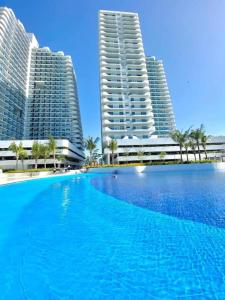 a large swimming pool in front of two tall buildings at Dtravellers Home 1 at AZURE NORTH BALI Tower in San Fernando