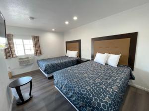 a hotel room with two beds and a chair at Palm Inn in Mojave
