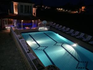 a swimming pool at night with chairs around it at Athina Studios in Argasi