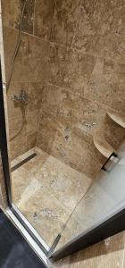 um chuveiro com uma porta de vidro com uma torneira em Appartement Kantar - Tout en Rose em Anduze
