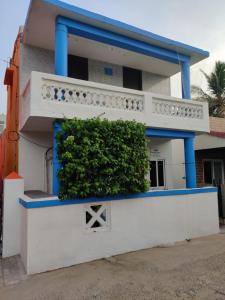 a blue and white house with a bush in front at The Sea Shelter Home Stay in Mahabalipuram