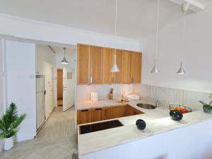 a kitchen with white counters and wooden cabinets at Beach Serenity Studio on Makenzy in Larnaka