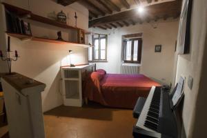 - une petite chambre avec un lit et un piano dans l'établissement Appartamento nel Borgo, à Roccatederighi