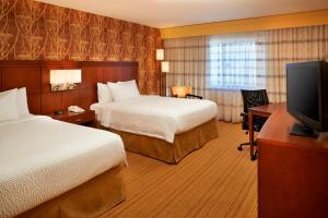 a hotel room with two beds and a flat screen tv at Courtyard Detroit Utica in Utica