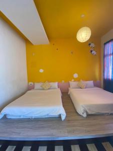 two beds in a room with a yellow wall at Lazy Sheeps Hostel in Hengchun South Gate