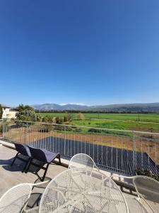 een balkon met tafels en stoelen en uitzicht op een veld bij היחידה ליד הנחל עם הנוף לחרמון 33 in Sede Neẖemya