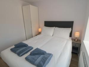 a bedroom with a white bed with two towels on it at 2 Staveley Cottages in Weaverthorpe