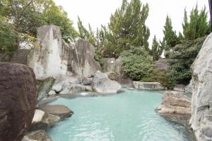 una piscina de agua con rocas en un jardín en Hotel Heian, en Fuefuki