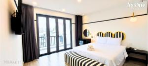 a bedroom with a white bed and a large window at As ONE Hotel Biên Hòa in Bien Hoa