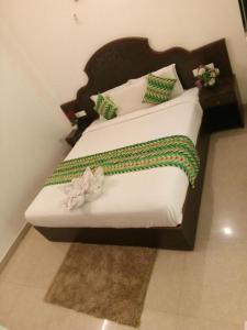 a bedroom with two beds with green and white pillows at Ebenezer Plaza in Nedumbassery