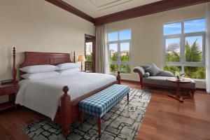 Danang Marriott Resort & Spa في دا نانغ: غرفة نوم بسرير وكرسي ونوافذ