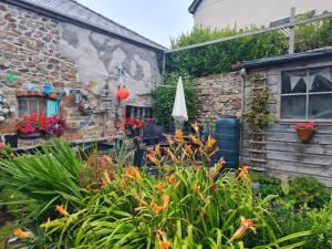 a garden with flowers and an umbrella at Anvil House, The Old Forge in Saint Erth