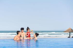 a family sitting in the swimming pool at the beach at Danang Marriott Resort & Spa in Da Nang